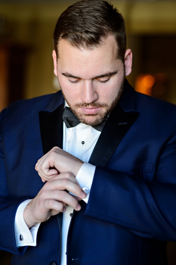 A groom putting on his new cufflinks before the ceremony.